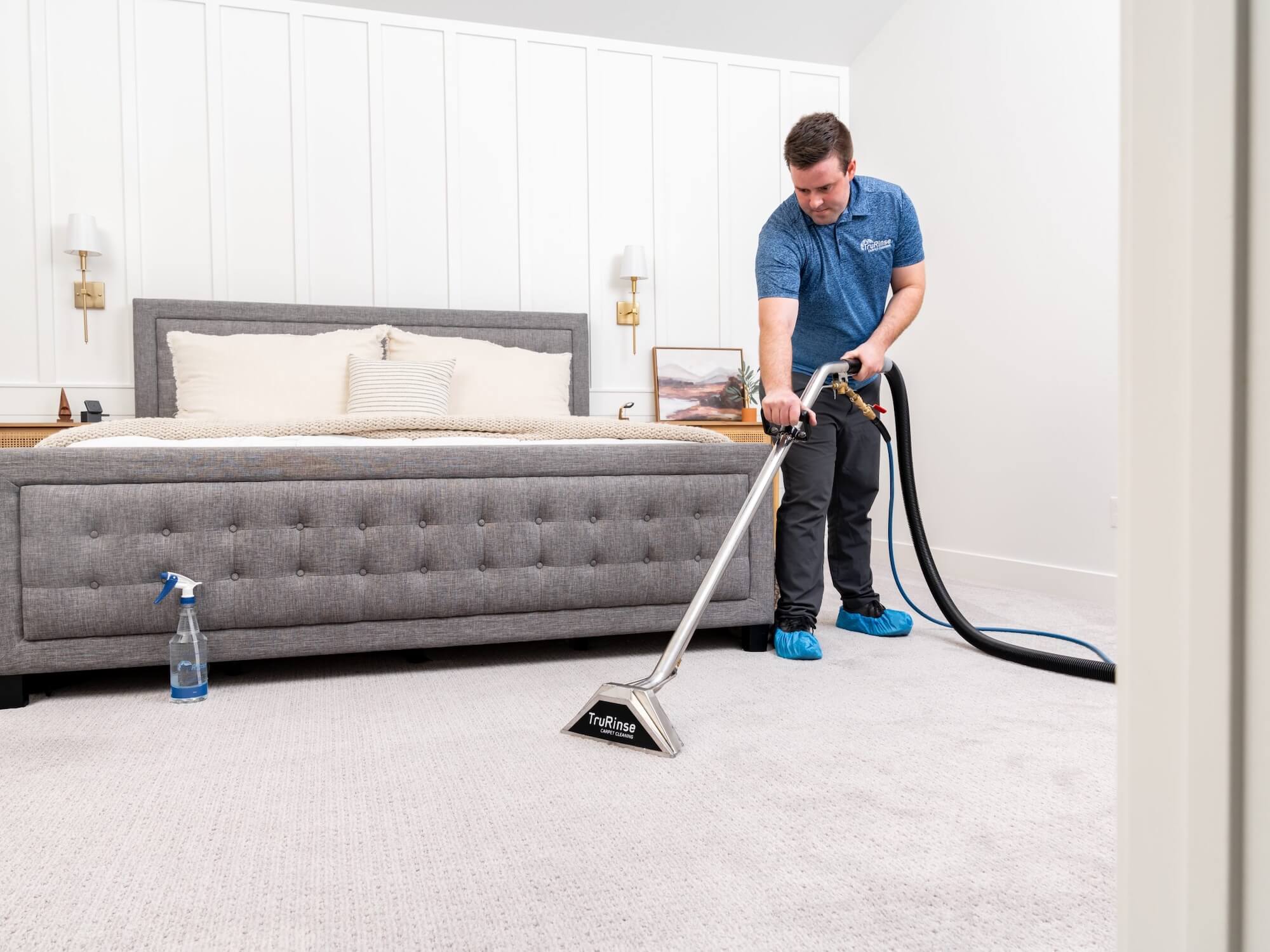 man performing professional carpet cleaning on white bedroom carpet